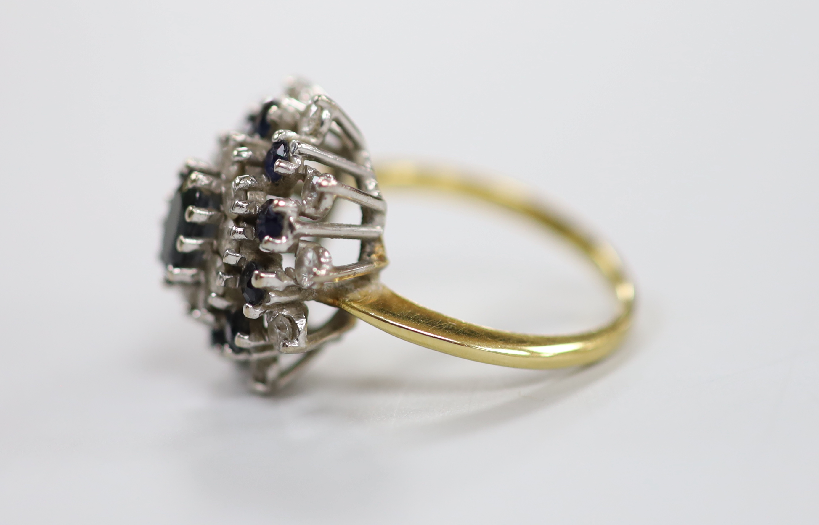 An 18ct yellow metal, sapphire and diamond set oval cluster dress ring, size M, gross weight 6 grams.